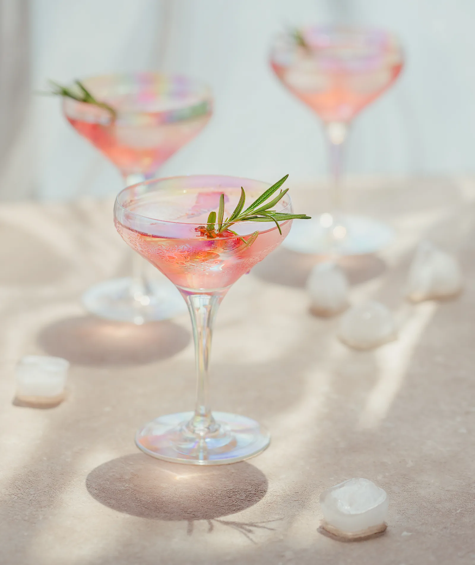 Cocktail rosati con rosmarino su una superficie chiara